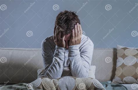 Young Sad And Desperate Man At Home Sitting At Sofa Couch Holding Head