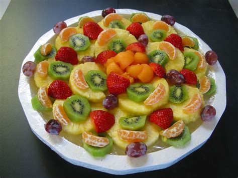 A Fruit Salad On A White Plate Topped With Kiwis Oranges And Strawberries