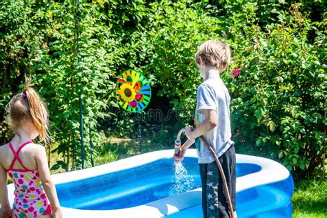 Little Boy And Girl Filling Swimming Pool With Water Stock Photo