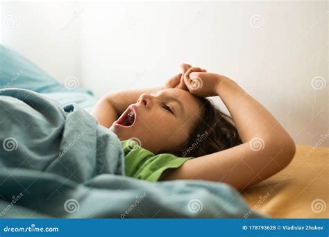 The Child Yawns While Lying In Bed The Boy Stretches While Waking Up