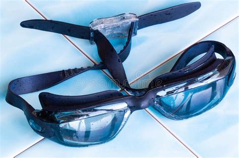 Swimming Goggles With Water Drops On Glass On The Blue Ceramic Tiles