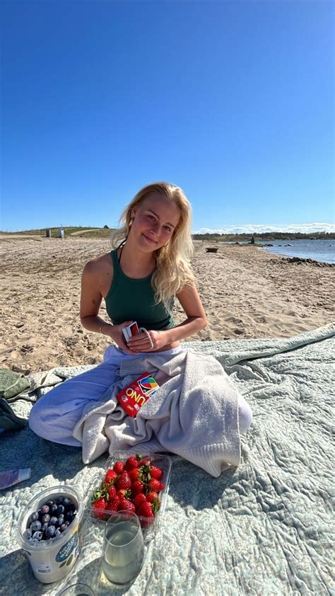 A Woman Is Sitting On The Beach With Strawberries And Blueberries In
