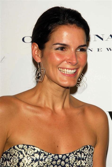 A Woman In A Strapless Dress Smiles For The Camera While Wearing Large