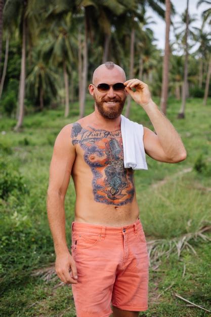 셔츠없이 정글 열대 필드에 문신을 한 강한 남자 무료 사진