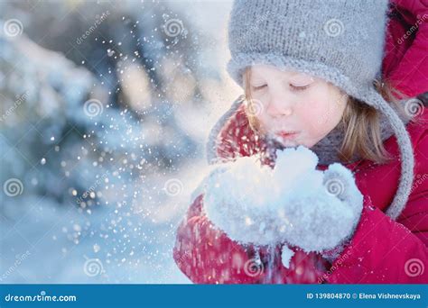 Winter Fun A Girl In Warm Clothes Is Playing With Snow Stock Photo
