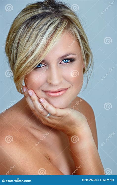 Beautiful Blond Model With Nude Make Up Slicked Back Hair And Naked Shoulders Holding Her Face