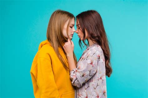 Dos mujeres lesbianas íntimas casi besándose aislado sobre amarillo