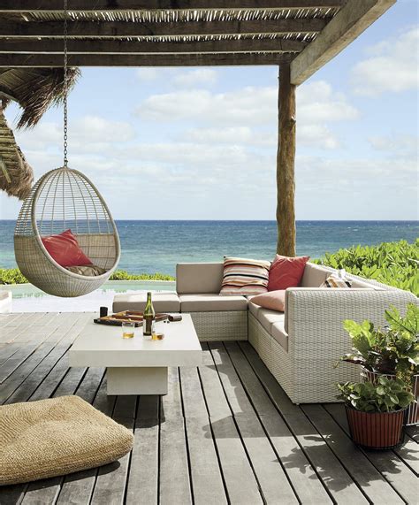 An Outdoor Living Area Overlooking The Ocean With Hanging Chairs And