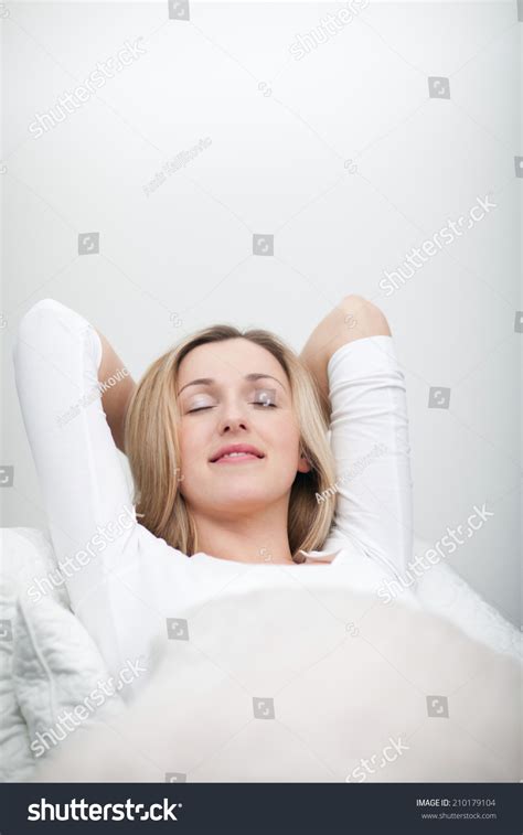 Blissful Young Woman Relaxing In Bed Stretched Out On Her Back With Her