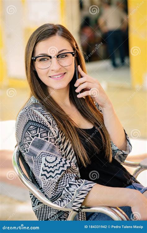 Young Girl With Glasses Talking On The Phone While Working On Her