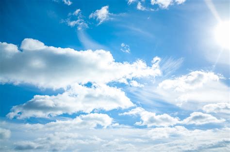 Bright Blue Sky With White Fluffy Clouds And Shining Sun Background