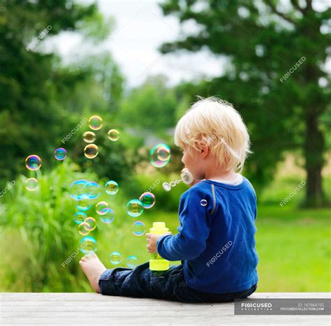Boy Blowing Bubbles On Porch — Sitting Blond Stock Photo 167664150