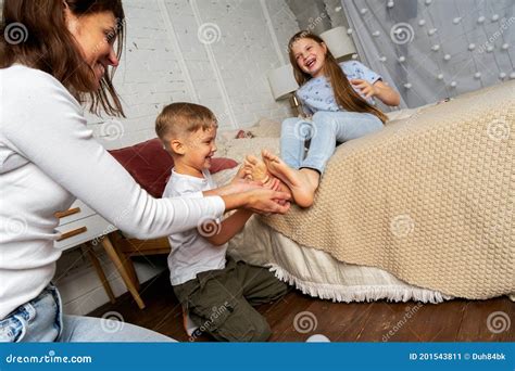 Mom In The Bedroom On The Bed Fun Tickles The Legs Of Children Boys