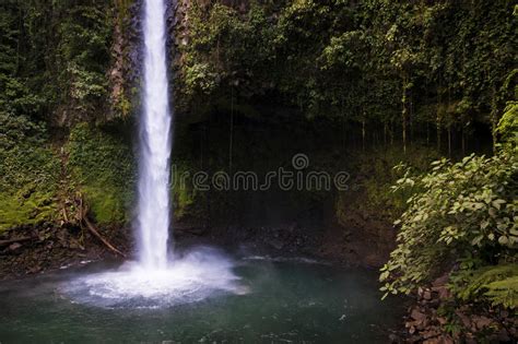 View Of The La Fortuna Waterfall With One Man Standing On A Rock In