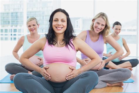 happy pregnant women in yoga class holding their bumps in a fitn instema formación para