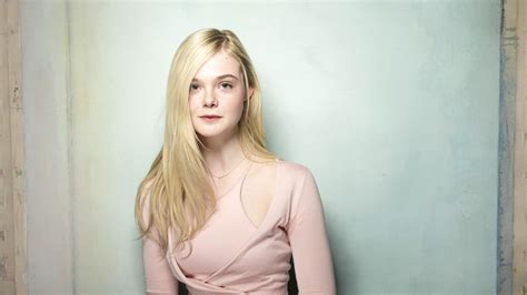 Mary Elle Fanning Is Sitting With Background Of Blue Painted Wall Hd