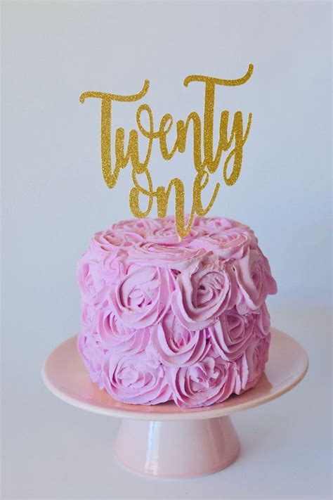 A Cake With Pink Frosting And Gold Lettering On Top Sitting On A Plate