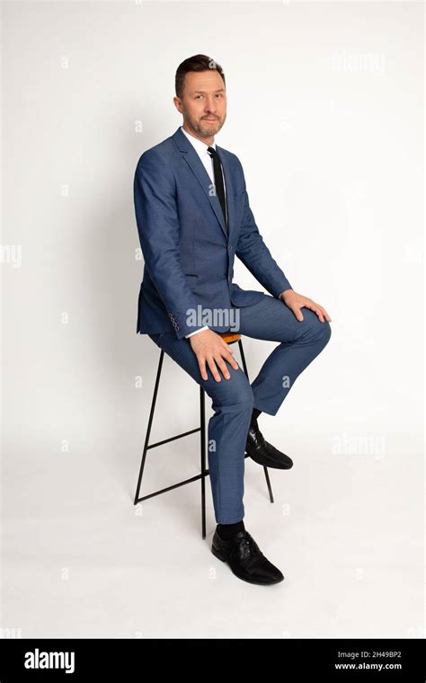 Full Length Portrait Of Man In Suit Sitting On Chair Isolated On White
