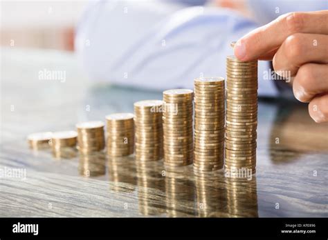 Business Person Placing Coin Over The Increasing Coins Stack On Office