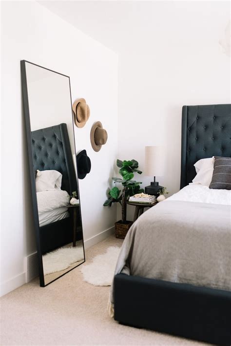 A Bedroom With A Bed Mirror And Side Table