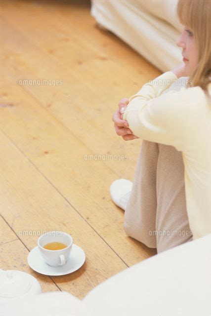 ソファの前の床に座った女性[21007004334]の写真素材・イラスト素材｜アマナイメージズ
