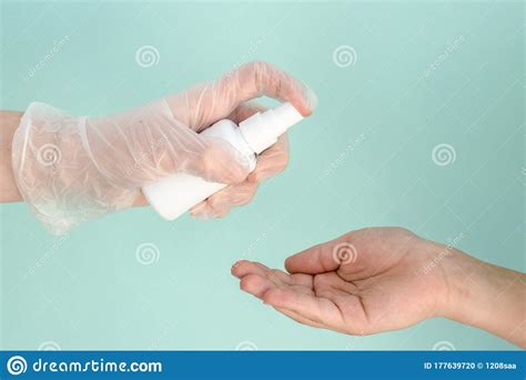 Hand In Medical Glove Holds White Bottle Of Antibacterial Sanitizer For