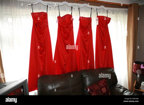 four 4 bright red brides maids dresses hanging from a window in a house on a wedding day morning