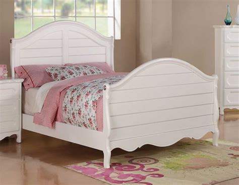 A White Bed Sitting In A Bedroom Next To A Dresser And Mirror On Top Of A Wooden Floor