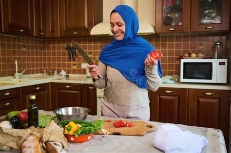 arabic pretty woman housewife in blue hijab smiling a toothy smile looking at camera standing