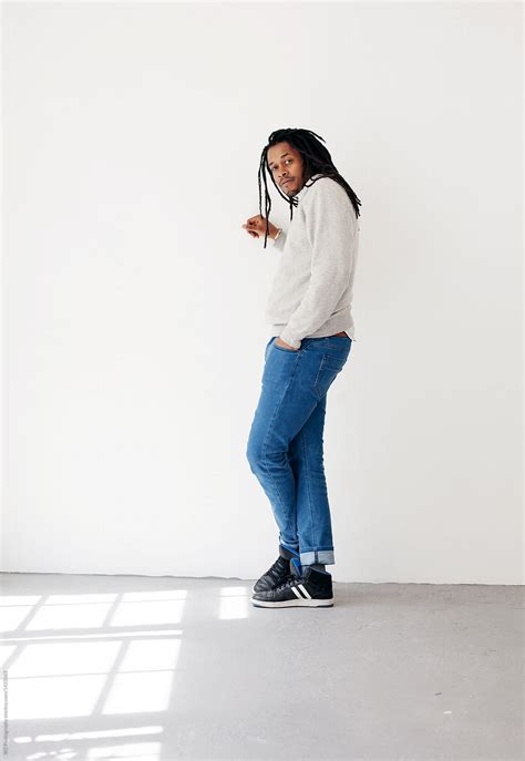 full body portrait of black man leaning on a white wall by stocksy contributor w2