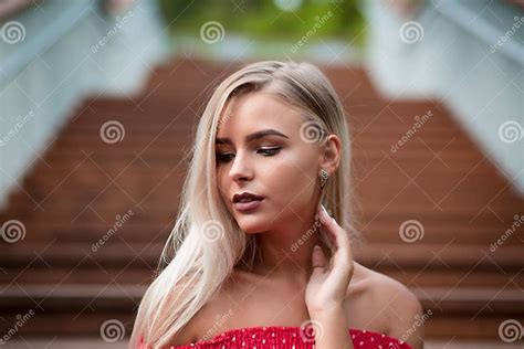 Romantic Blonde Girl With Naked Shoulders Wearing Red Dress Posing On