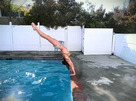 a woman diving into a swimming pool with her legs in the air while standing on one leg