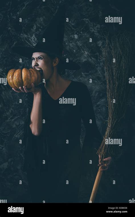 Halloween Witch Holding A Pumpkin And A Broom Stock Photo Alamy