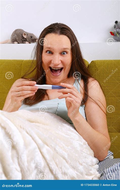 Mujer Joven En Cama Mira La Prueba De Embarazo Excitada Foto De Archivo