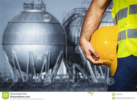 Hand Or Arm Of Engineer Hold Yellow Plastic Helmet In Front Of Oil