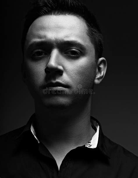 Young Man Looking Serious In Black Shirt On Grey Studio Dark Shadow