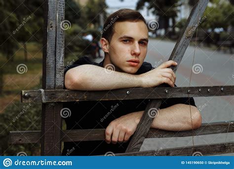Attractive Guy On The Street In Black Leaning On A Hedgefence Stock