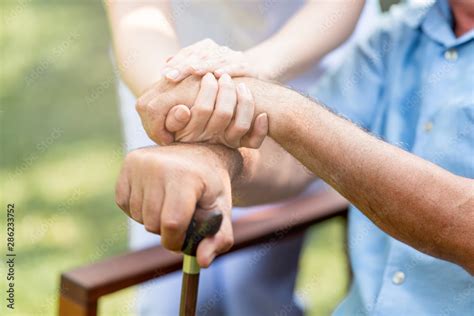 Caring Nurse Helping Senior Man Sitting On Bench In Gaden Asian Woman Caucasian Man Holding