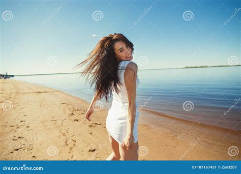 Portrait Of Beautiful Happy Girl On The Sand City Beach With Sea