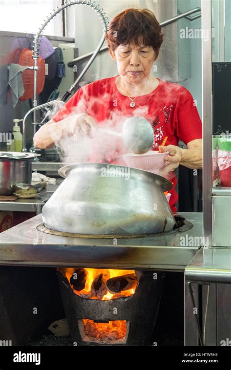 A Singaporean Woman Cooking And Ladling A Traditional Nyonya Curry Soup