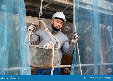 Worker Lowering Down Bucket With Construction Mortar Stock Image