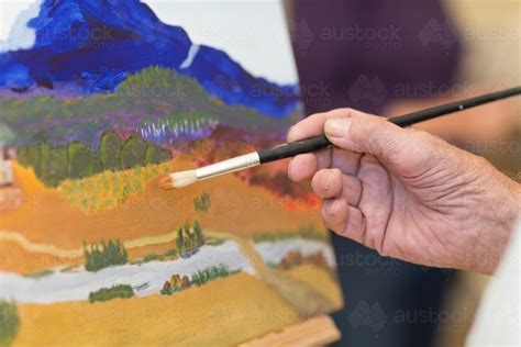 Image Of Close Up Of Artists Hand Holding Paint Brush With Painting