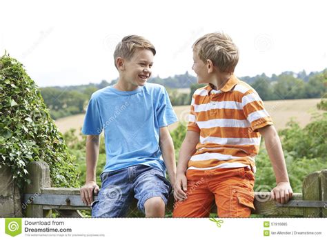 The american language is quite easy and you can learn it. Two Boys Sitting On Gate Chatting Together Stock Image - Image of adolescent, child: 57916885