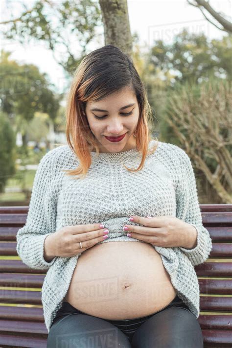 Portrait Of A Young Pregnant Woman Showing Her Belly At The Park