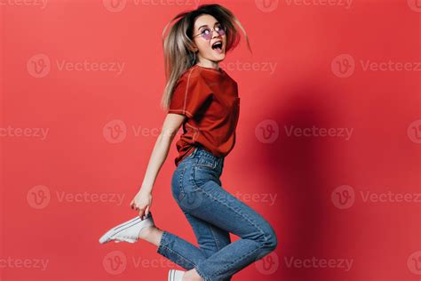 Perky Girl In Red T Shirt And Jeans Jumping On Isolated Background