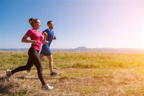 Young Couple Jogging On Sunny Day At Summer Mountain Stock Photo