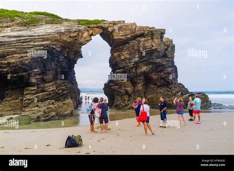 Group Of Tourists By A Stone Arch At Beach Of The Cathedrals Natural