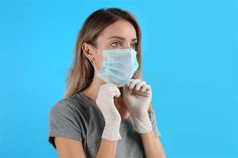 Woman In Medical Gloves Putting On Protective Face Mask Against Light