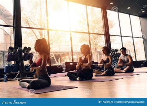 Group Of Asian Women And Man Doing Pilates Lying On Yoga Mats In