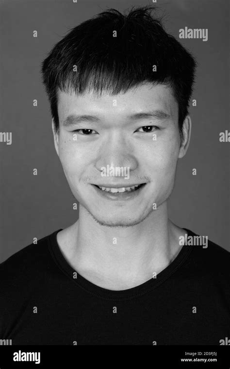 Studio Shot Of Young Chinese Man Against Gray Background Stock Photo